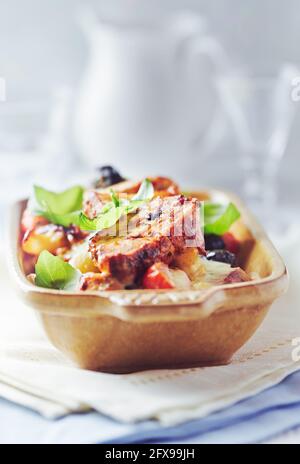 Filetto di maiale al forno con pasta Penne, pomodori ciliegini, olive nere e formaggio. Sfondo luminoso. Primo piano Foto Stock