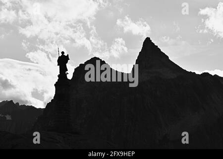 Statua e vetta di montagna in serata al Passo del Gran San Bernardo collega Martigny nel Cantone Vallese, Svizzera con Aosta, Italia Foto Stock