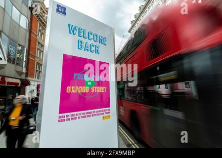 Londra, Regno Unito. 26 maggio 2021. Una donna e un autobus a due piani passano un cartello Welcome Back (Bentornato) su Oxford Street, mentre i rivenditori sperano che l'allentamento della chiusura dei negozi comporti un aumento delle vendite come prova della domanda di clienti. Credit: Stephen Chung / Alamy Live News Foto Stock