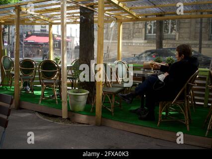 A Parisian woman enjoys an evening drink on a temporary Paris cafe terrace, built to enable customers to drink outside after Covid-19 restrictions are lifted - Le Montmartre Café, Rue Custine, 75018, Paris, France Stock Photo