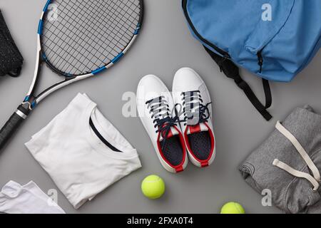 Racchetta da tennis e scarpe su sfondo grigio Foto Stock