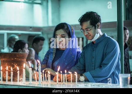 Dhaka, Bangladesh. 26 Maggio 2021. I devoti buddisti illuminano le candele di fronte ad una statua del Signore Buddha durante le celebrazioni. Buddha Purnima, il più grande festival religioso della Comunità buddista, segna l'avvento, il raggiungimento del nirvana (o illuminazione) e la partenza del Signore Gautama Buddha. Credit: SOPA Images Limited/Alamy Live News Foto Stock