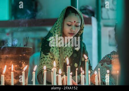 Dhaka, Bangladesh. 26 Maggio 2021. Un devoto buddista ha visto le candele di illuminazione di fronte a una statua del Signore Buddha durante le celebrazioni. Buddha Purnima, il più grande festival religioso della Comunità buddista, segna l'avvento, il raggiungimento del nirvana (o illuminazione) e la partenza del Signore Gautama Buddha. Credit: SOPA Images Limited/Alamy Live News Foto Stock