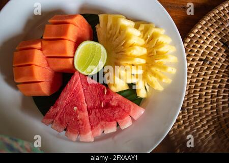 Dieta, insalata di frutta mista sana nel piatto bianco su un tavolo di legno con bel decor - colazione sana, concetto di perdita di peso Foto Stock