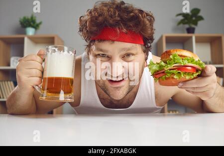 Felice uomo soddisfatto godere di mangiare hamburger bere birra Closeup faccia verticale Foto Stock