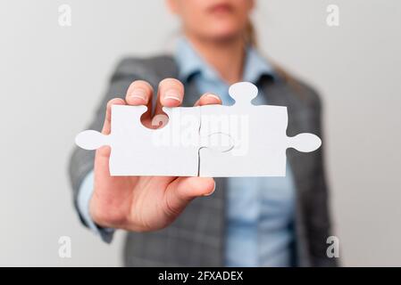 Welldressed Business Woman tenendo due pezzi di Jigsaw Puzzle, Donne professionali per adulti risolvere le idee mancanti, strategia per nuove idee Foto Stock