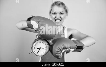 Sportive. vincere il giorno. arrabbiato donna guantoni da pugilato. ragazza boxer tenere premuto il tasto alarm clock. Mattina energia. pieno di potenza. tempo di attività. Che istituisce l'orologio Foto Stock