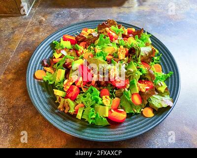 Piatto con insalata fresca fatta di lattuga, pomodori, carote e noci. Foto Stock