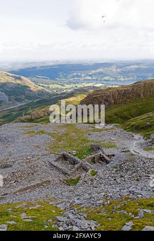 Parapendio sopra i resti dell'estrazione dell'ardesia sul vecchio uomo di Coniston a Cumbria, Inghilterra. Foto Stock