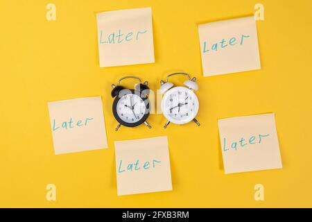 Sveglia con una nota appiccicosa con testo successivo. Concetto di procrastinazione, ritardo e urgenza. Foto Stock
