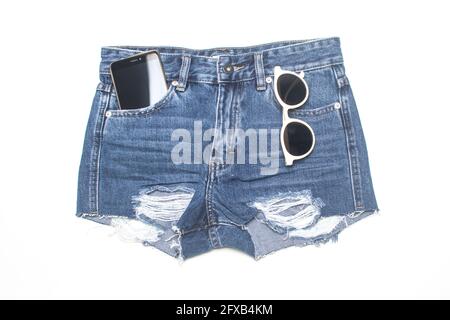 pantaloncini in denim con telefono e occhiali da sole in tasca isolato su bianco Foto Stock
