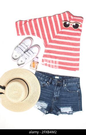 look estivo: camicia a righe, pantaloncini in denim, cappello di paglia, occhiali da sole e scarpe da ginnastica isolate su bianco. Foto Stock