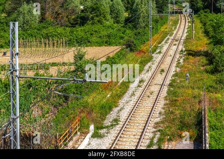 vista dall'alto di una linea ferroviaria a binario unico che attraversa campi coltivati e boschi. Abruzzo, Italia, Europa Foto Stock