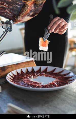 Chef femminile che prepara fette di prosciutto al ristorante Foto Stock