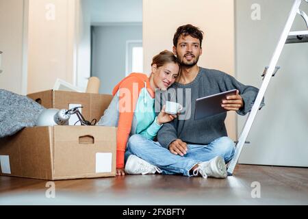 Giovane uomo seduto con la ragazza mentre si guarda via Foto Stock