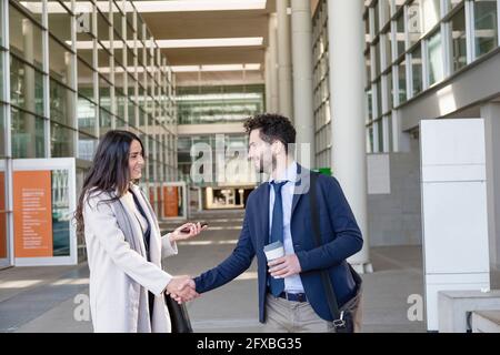 Imprenditori maschili e femminili che fanno stretta di mano mentre si levano in piedi sul sentiero Foto Stock