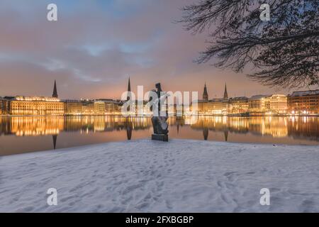 Germania, Amburgo, architettura cittadina illuminata che si riflette nel lago di Binnenalster al tramonto d'inverno Foto Stock