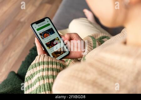 Giovane donna che ordina cibo sul telefono cellulare a casa Foto Stock