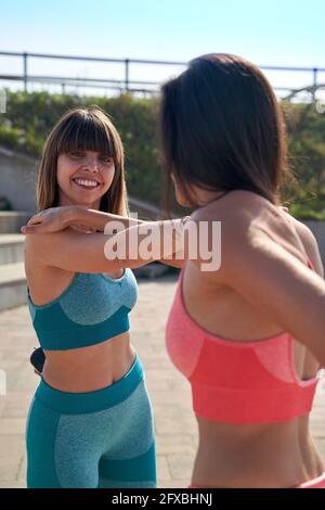 Atlete che fanno stretching durante la giornata di sole Foto Stock