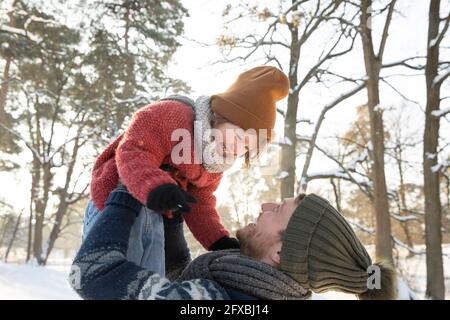 Il padre allegro solleva il figlio in abiti caldi durante l'inverno Foto Stock