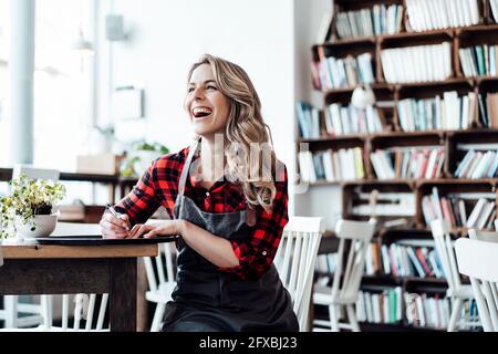 Donna felice padrona seduto al tavolo in una caffetteria Foto Stock