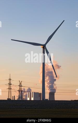 Germania, Renania Settentrionale Vestfalia, Grevenbroich, turbine eoliche e piloni elettrici al tramonto Foto Stock