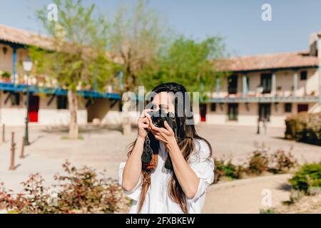 Giovane donna che fotografa attraverso la macchina fotografica al villaggio Foto Stock