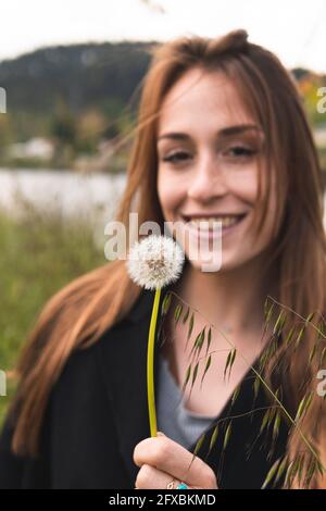 Bella donna sorridente mentre si guarda blowball Foto Stock