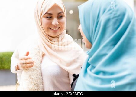 Giovane donna che guarda l'amica che indossa hijab blu Foto Stock