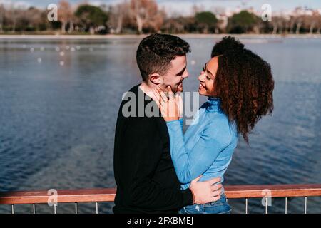Giovane coppia sorridente mentre si guarda l'un l'altro da ringhiera Foto Stock