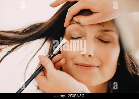 Donna make-up artista che applica l'ombra degli occhi sugli occhi della sposa in studio Foto Stock