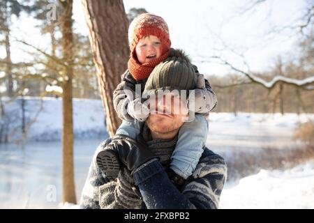 Padre che porta il figlio sulla spalla durante l'inverno Foto Stock