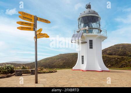 Nuova Zelanda, Isola del Nord, cartello direzionale di fronte al faro di ofÂ Reinga Foto Stock