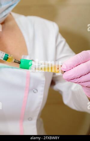 Lo specialista preleva il plasma ematico dalla provetta utilizzando una siringa. Plasmolifting, cosmetologia medica Foto Stock