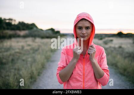 Bella donna con giacca con cappuccio in piedi sulla strada di campagna Foto Stock