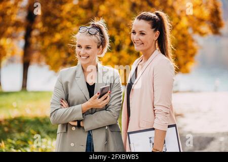 Donne sorridenti che indossano casual elegante in piedi insieme in giardino Foto Stock