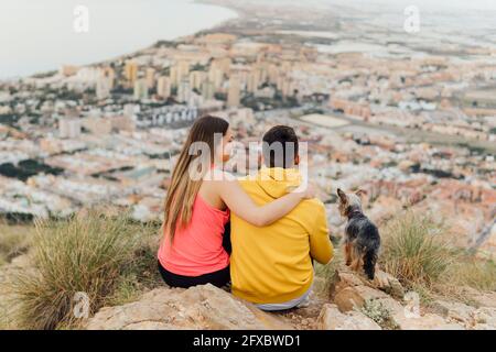 Coppia seduta dal cane in collina Foto Stock