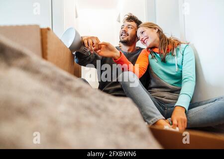 Felice giovane coppia seduta insieme mentre si guarda via Foto Stock
