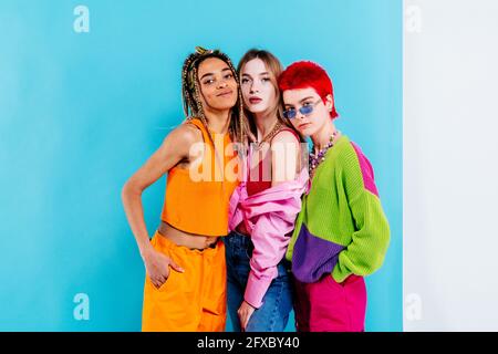 Eleganti amici femminili che si levano in piedi su sfondo blu Foto Stock