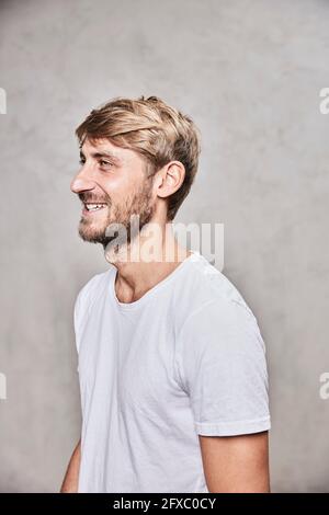 Bell'uomo sorridente mentre si guarda via dalla parete Foto Stock