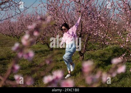 Donna di metà adulta che balla nel campo di pesca durante la giornata di sole Foto Stock