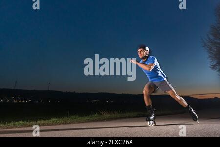 Giovane con pattinaggio su strada durante il tramonto Foto Stock