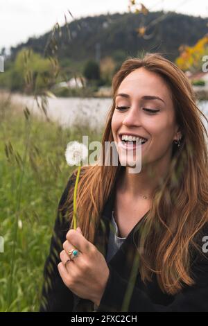 Donna allegra con blowball godendosi in natura Foto Stock