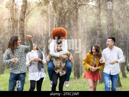 Giocosi amici maschili e femminili che si divertono nella foresta Foto Stock