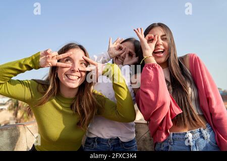 Divertenti amici femminili che fanno i volti mentre si godono sulla terrazza Foto Stock