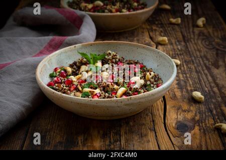 Ciotola di insalata di quinoa vegana con anacardi, semi di melograno e menta Foto Stock