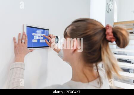 Giovane donna che usa il tablet digitale a casa Foto Stock