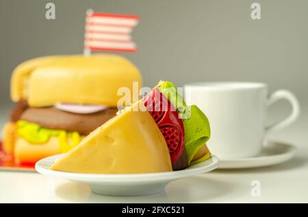 Pezzo della torta Burger, Madeira e torta stratificata di spugna di cioccolato, riempito con glassa ricoperta di glassa morbida e decorazioni di zucchero commestibile, torta i Foto Stock