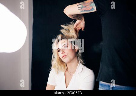 Donna parrucchiere styling capelli di modello in studio Foto Stock