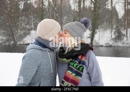 Coppia senior baciando mentre si trova al parco durante l'inverno Foto Stock